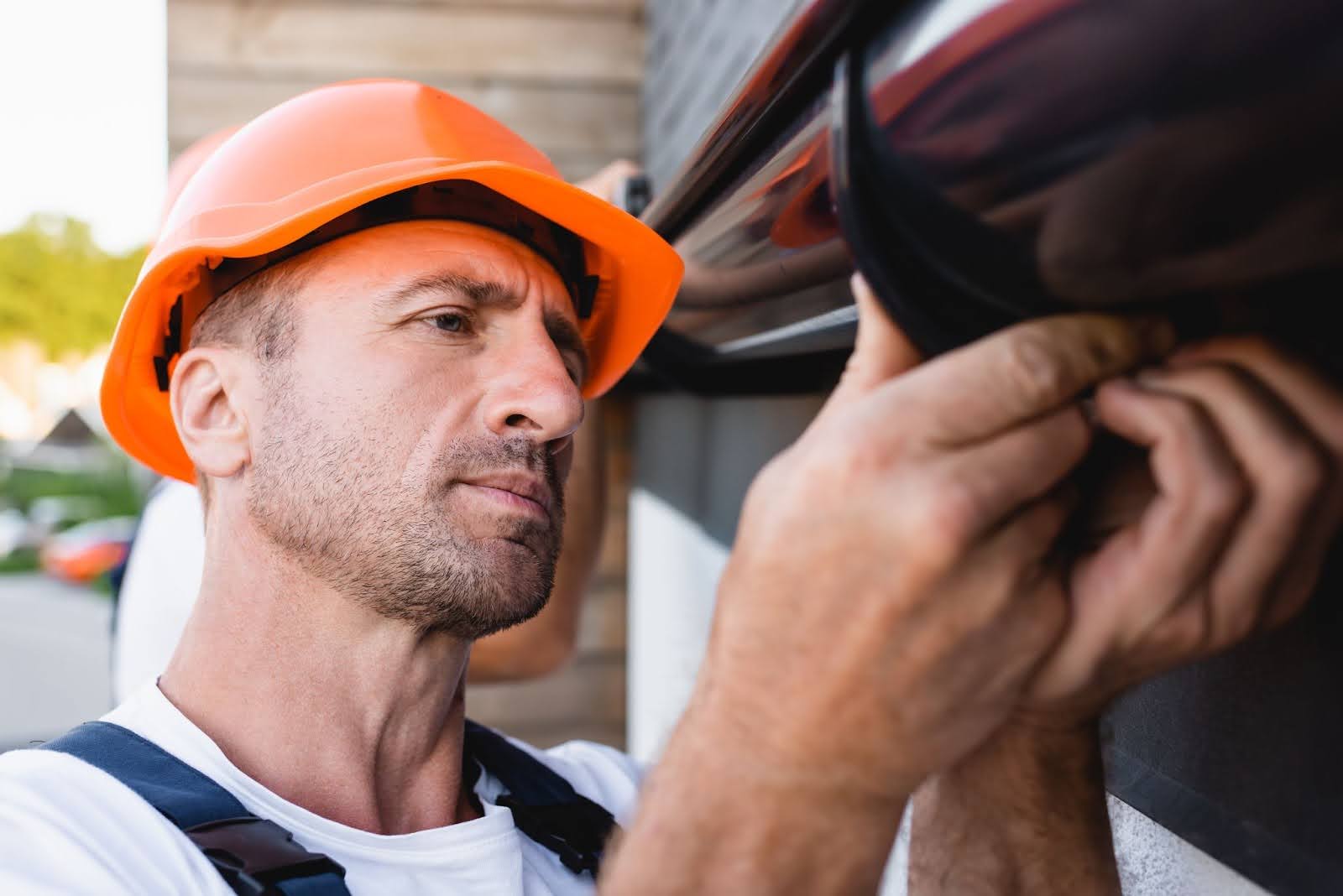 Worker adjusting rain gutter during detailed roof and gutter maintenance on a building exterior.