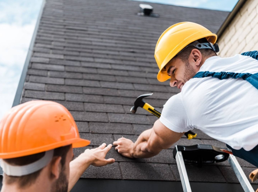 Two men in hard hats working on a roof repair.
