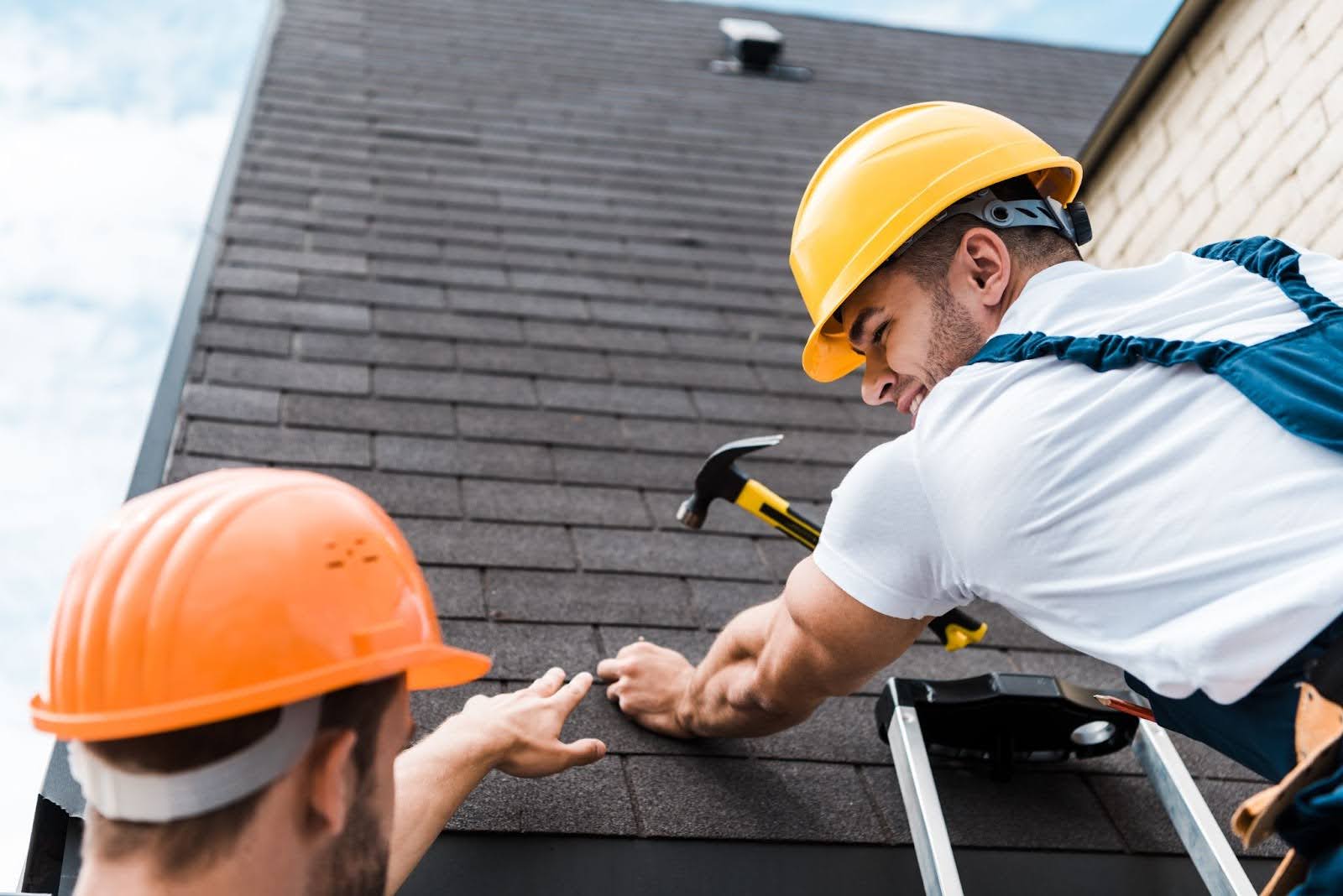 Two men in hard hats working on a roof repair.
