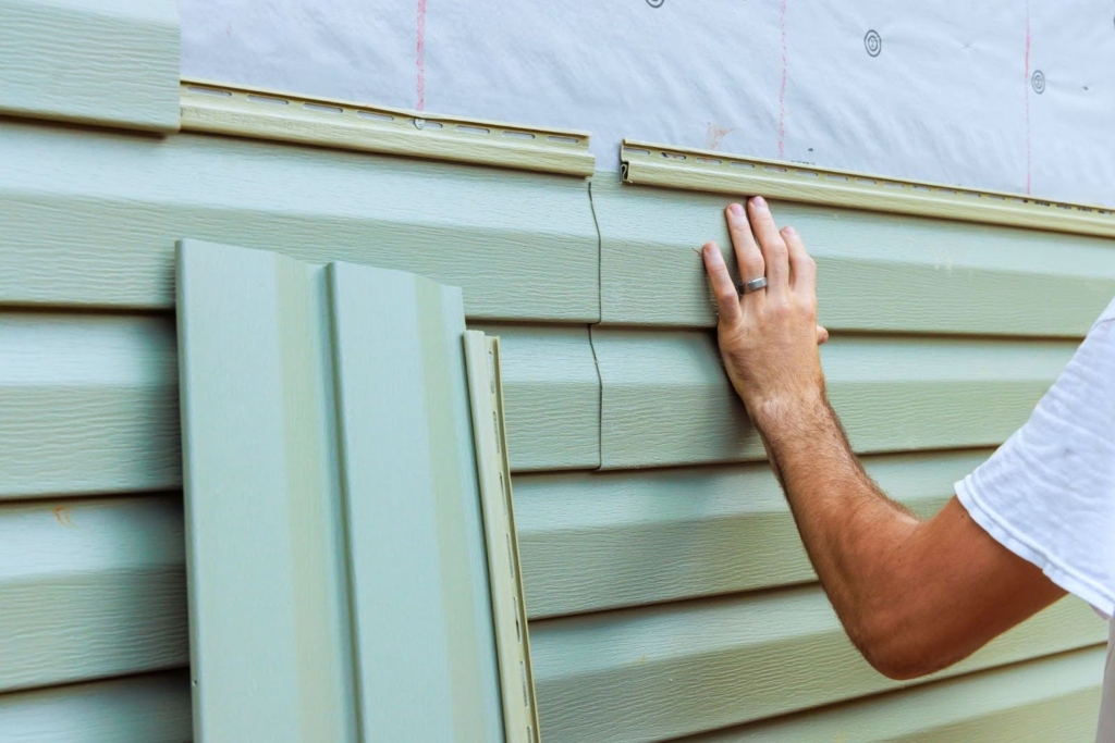 Man installing siding on a home.